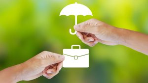 image of two hands holding white icons of a briefcase and an umbrella on a green bokeh background