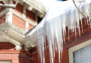 Closeup of ice and snow buildup and ice dam on the roof of an older home